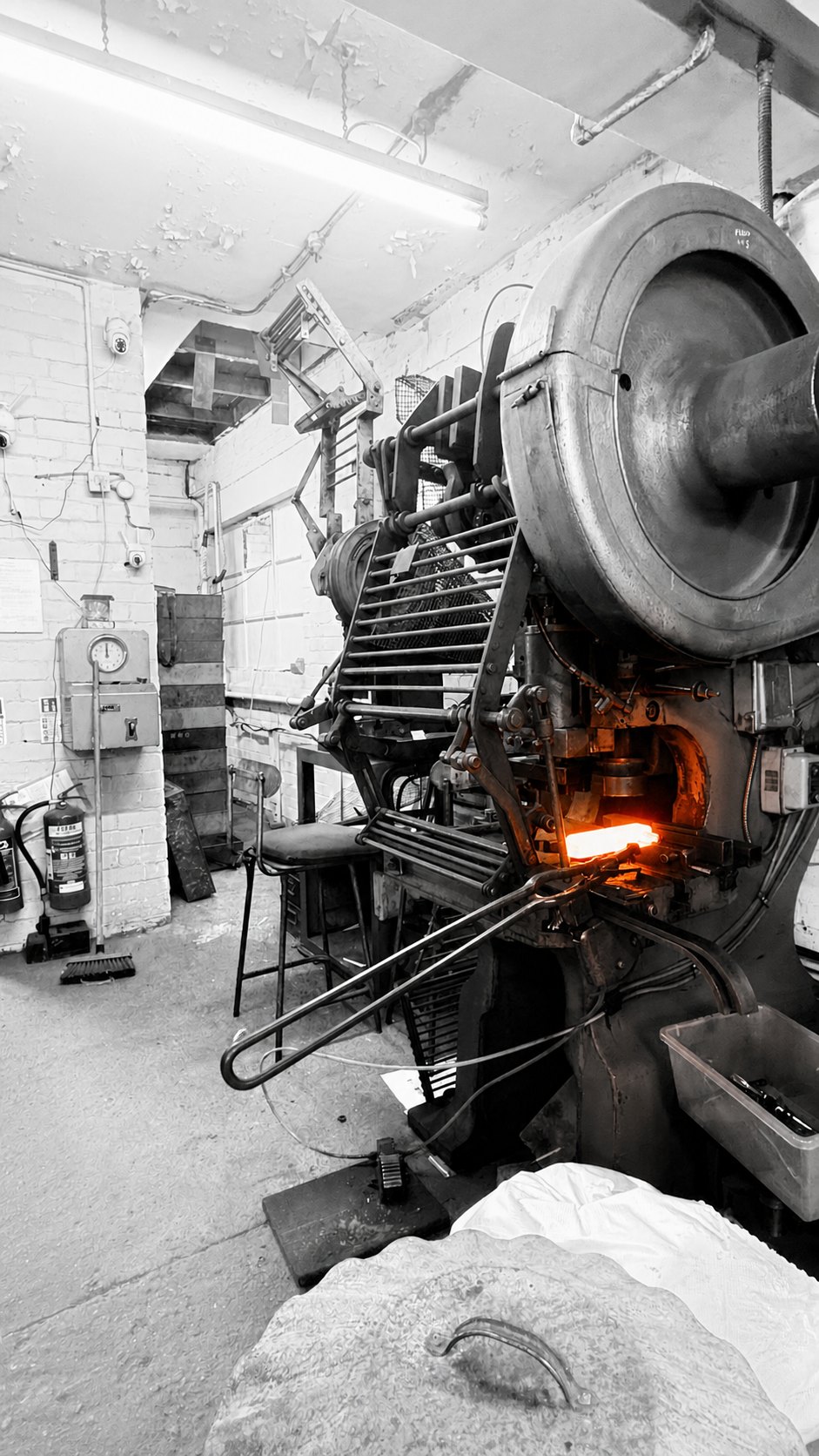 White-hot steel held in tongs at a forging press